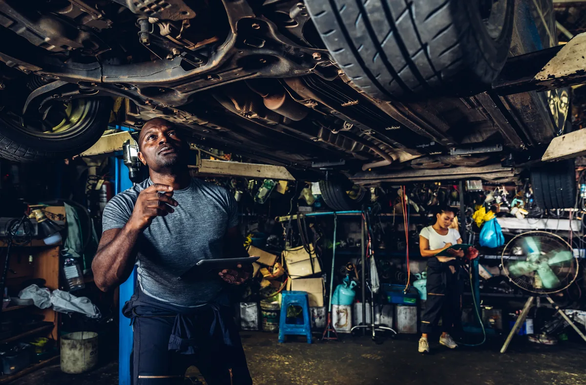 A technician inspecting a vehicle on a ramp