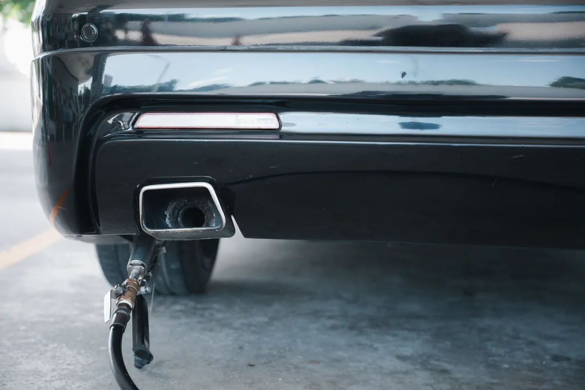 Exhaust gas analyser probe inserted into a car tailpipe during an emissions test
